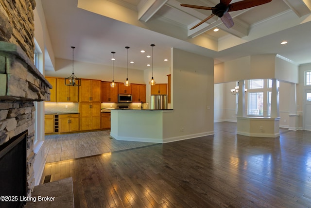 unfurnished living room with dark wood finished floors, coffered ceiling, ceiling fan with notable chandelier, a fireplace, and crown molding