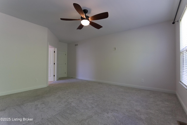 empty room featuring light colored carpet, ceiling fan, visible vents, plenty of natural light, and baseboards