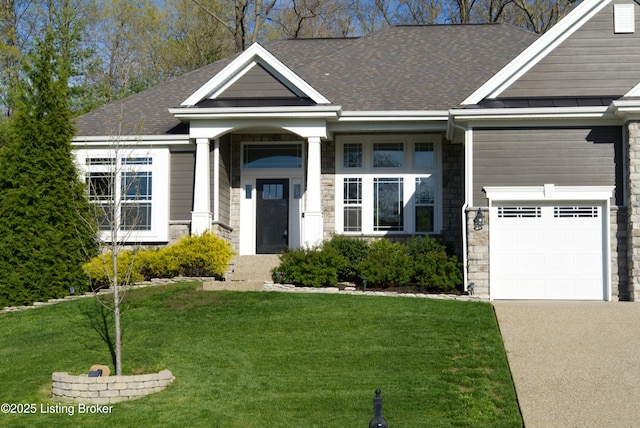 view of front of house featuring roof with shingles, a front yard, concrete driveway, and stone siding