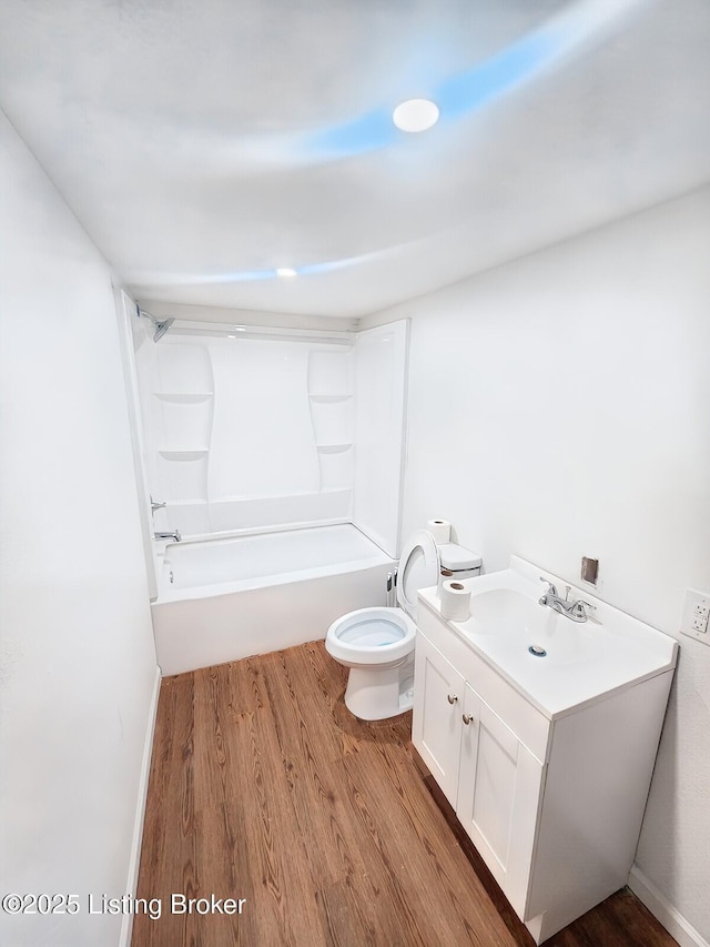 full bath featuring toilet, shower / washtub combination, wood finished floors, baseboards, and vanity