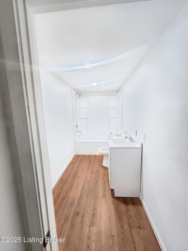 bathroom with toilet, vanity, baseboards, and wood finished floors