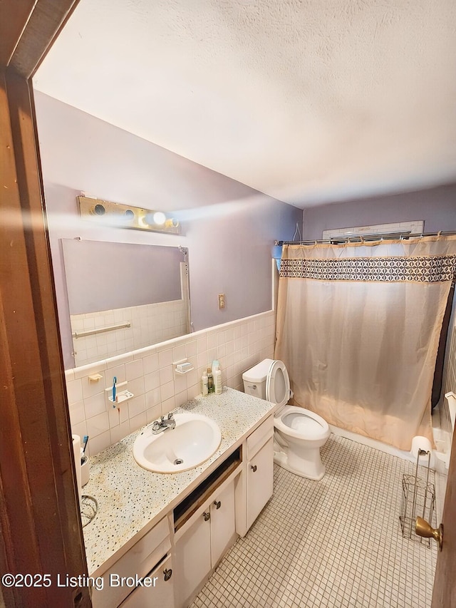 full bathroom featuring vanity, tile patterned flooring, a textured ceiling, tile walls, and toilet