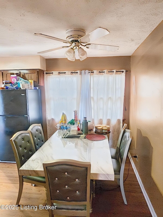 dining space with light wood finished floors, a textured ceiling, and ceiling fan