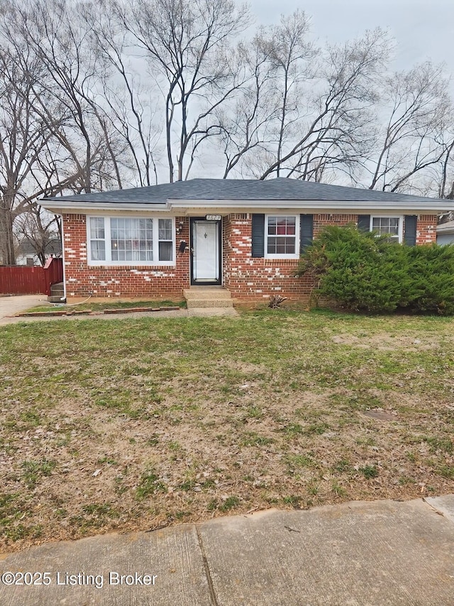 ranch-style house with entry steps, a front lawn, fence, and brick siding