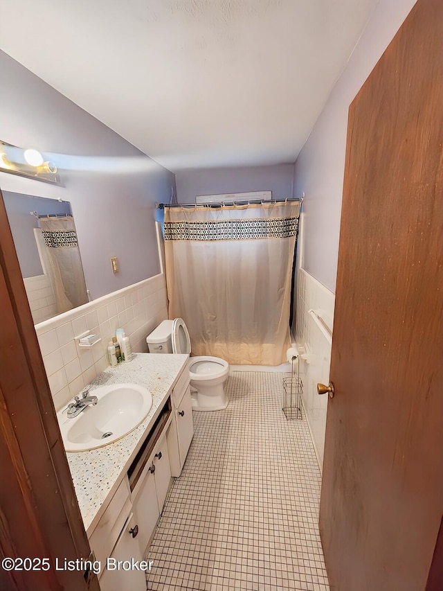 full bathroom with vanity, shower / bath combination with curtain, tile patterned floors, toilet, and tile walls