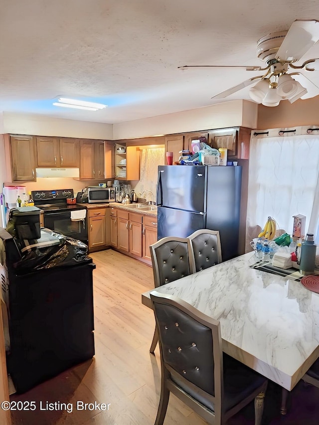 kitchen featuring black / electric stove, light wood finished floors, freestanding refrigerator, under cabinet range hood, and stainless steel microwave