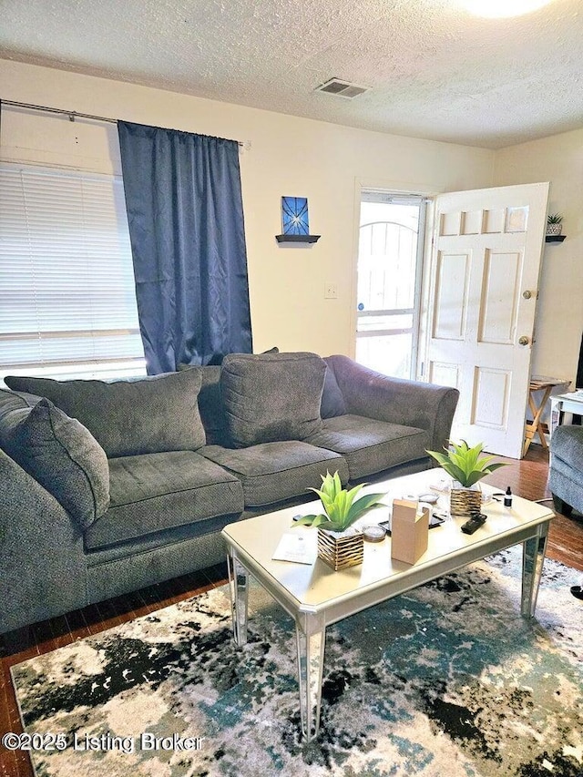 living room featuring visible vents, a textured ceiling, and wood finished floors