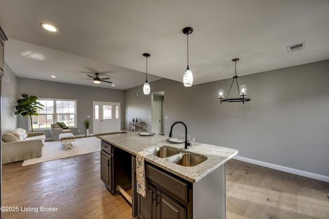 kitchen with open floor plan, ceiling fan with notable chandelier, visible vents, and a sink