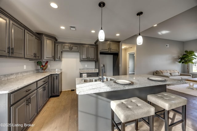 kitchen with a breakfast bar area, light wood-type flooring, recessed lighting, hanging light fixtures, and a sink