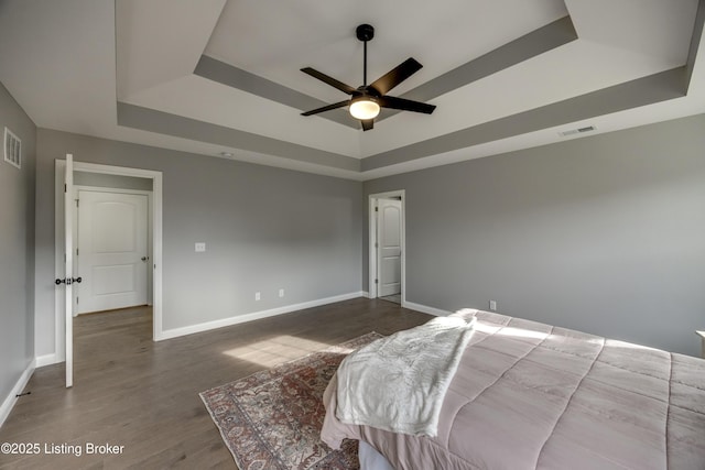 bedroom featuring visible vents, a raised ceiling, baseboards, and dark wood finished floors