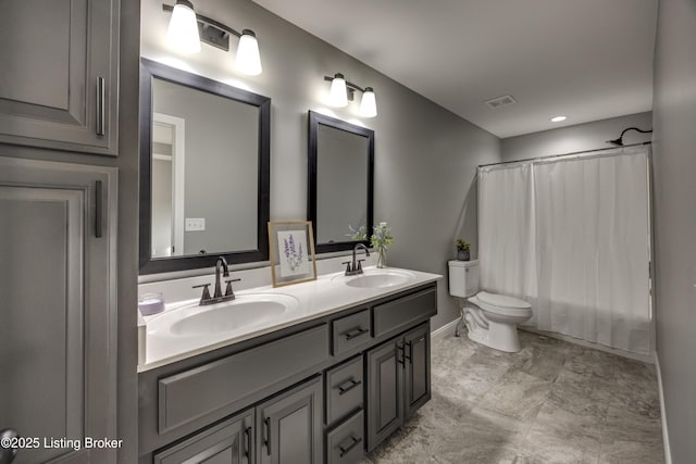 bathroom featuring double vanity, toilet, visible vents, and a sink