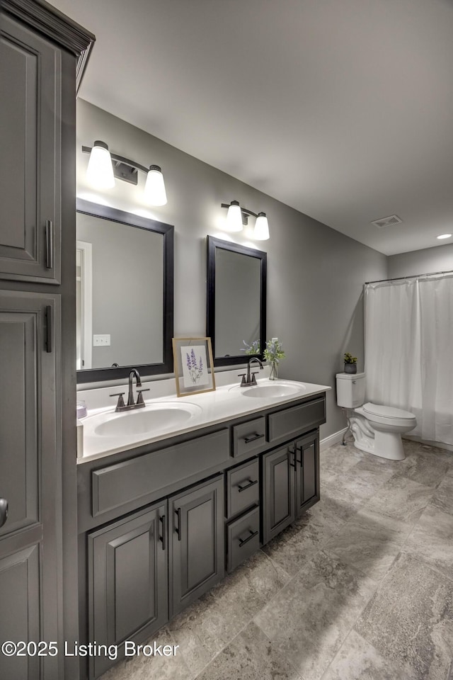 bathroom with a sink, visible vents, toilet, and double vanity