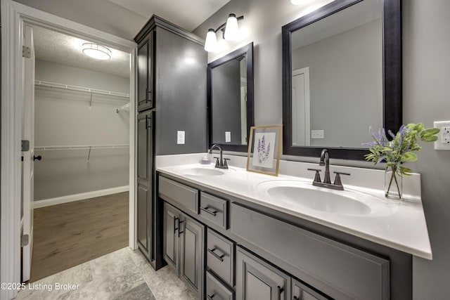 full bathroom with a sink, a textured ceiling, a spacious closet, and double vanity