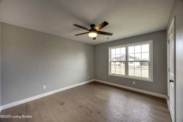 unfurnished room with wood finished floors, visible vents, baseboards, and ceiling fan