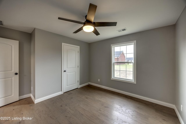 unfurnished bedroom with wood finished floors, baseboards, visible vents, and ceiling fan