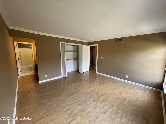 unfurnished bedroom featuring visible vents, baseboards, wood finished floors, and ornamental molding