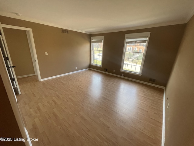 empty room with visible vents, ornamental molding, and light wood finished floors