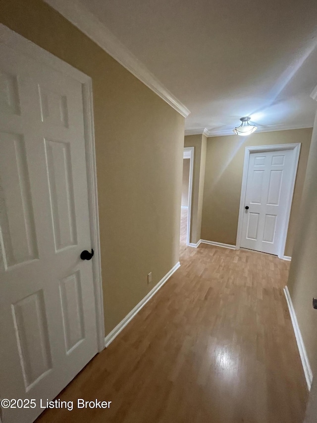 hall with baseboards, light wood-style floors, and ornamental molding