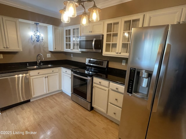 kitchen featuring crown molding, light wood-style flooring, appliances with stainless steel finishes, and a sink