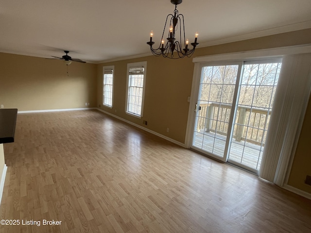 empty room with ceiling fan with notable chandelier, wood finished floors, baseboards, and ornamental molding