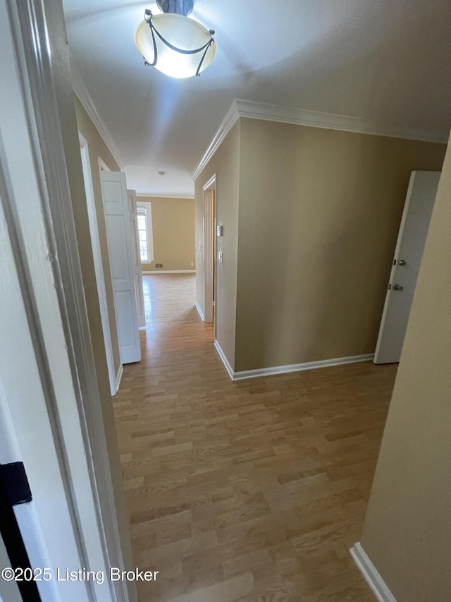 hall with baseboards, light wood-style flooring, and crown molding