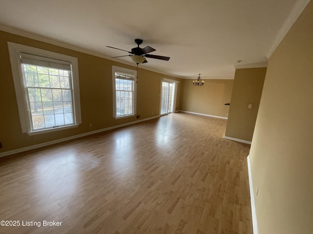 spare room featuring ceiling fan with notable chandelier, crown molding, baseboards, and wood finished floors