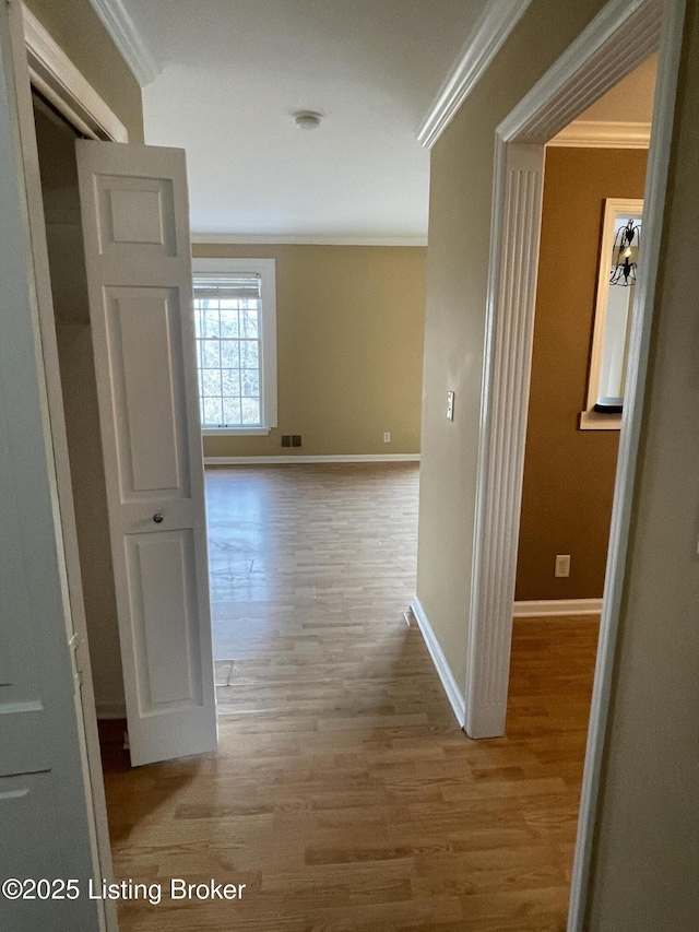 hall with visible vents, crown molding, baseboards, and wood finished floors