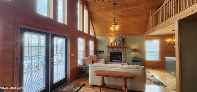 living area with a ceiling fan, a fireplace, french doors, wooden ceiling, and light wood-type flooring