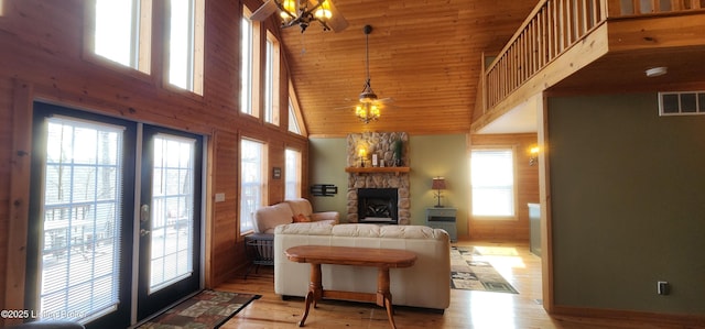 living room featuring visible vents, light wood finished floors, a high ceiling, a fireplace, and french doors