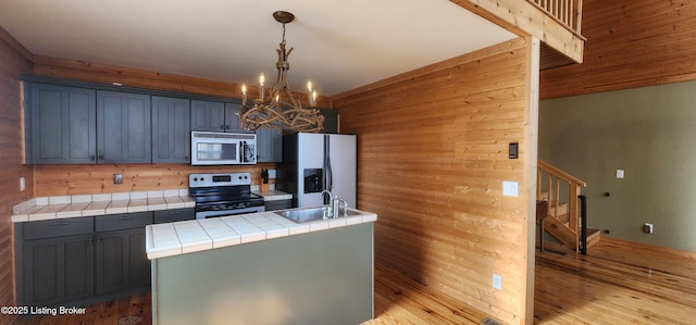 kitchen featuring tile countertops, refrigerator with ice dispenser, stainless steel range with electric cooktop, a notable chandelier, and light wood-type flooring