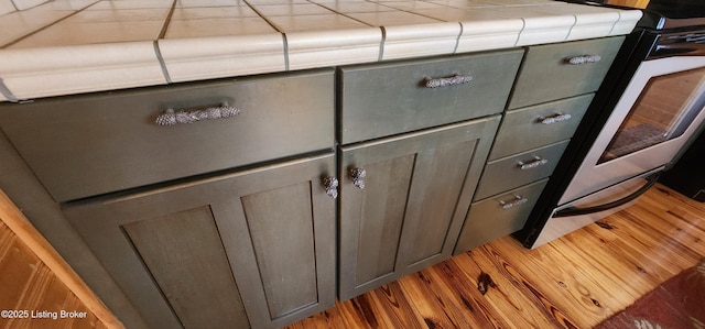 details featuring range, wood finished floors, gray cabinetry, and tile counters