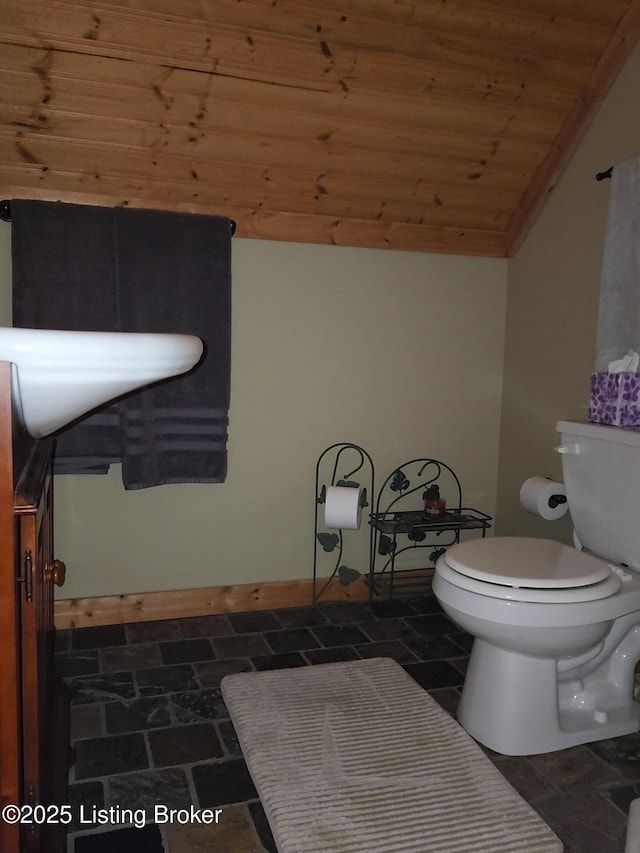 half bathroom with toilet, wood ceiling, stone finish flooring, and lofted ceiling