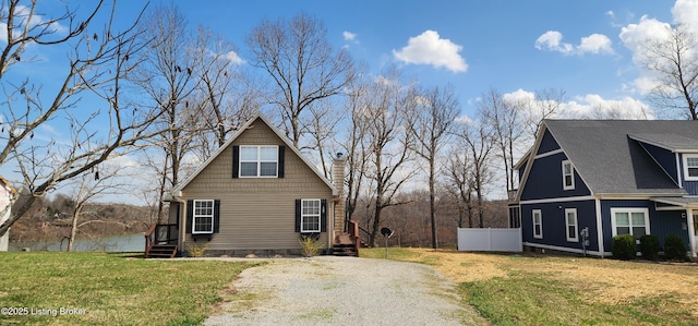 view of side of home with a lawn, a chimney, gravel driveway, and fence