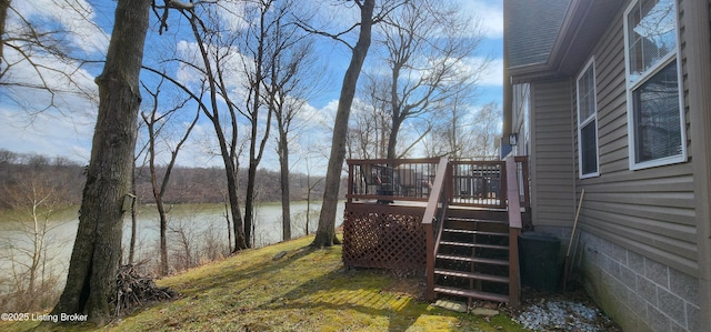 view of yard featuring stairway and a deck with water view