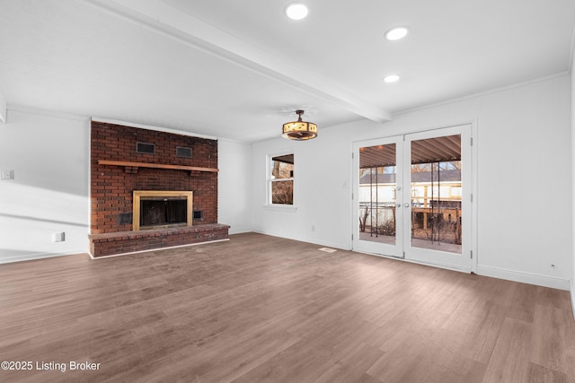 unfurnished living room featuring baseboards, beamed ceiling, recessed lighting, a fireplace, and wood finished floors