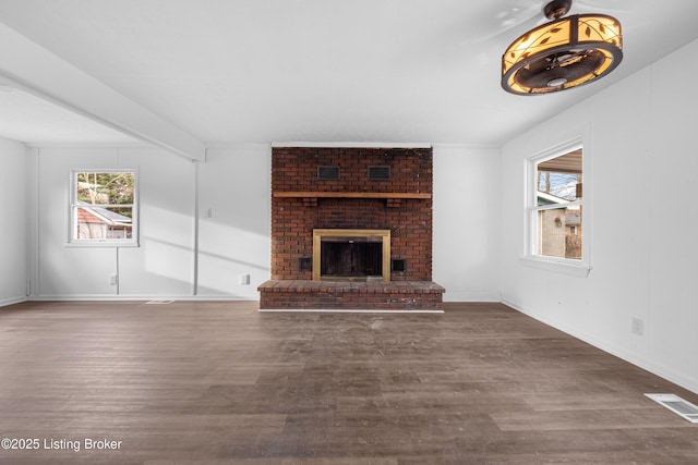 unfurnished living room with beam ceiling, visible vents, a fireplace, and wood finished floors