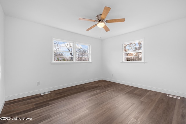 empty room with a wealth of natural light, visible vents, and wood finished floors