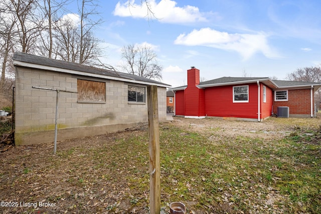 back of property featuring roof with shingles, central AC, and a chimney