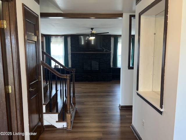 foyer featuring baseboards, stairs, wood finished floors, a glass covered fireplace, and a ceiling fan