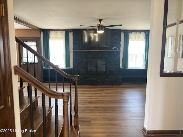 unfurnished living room featuring a wealth of natural light, stairway, a ceiling fan, and wood finished floors