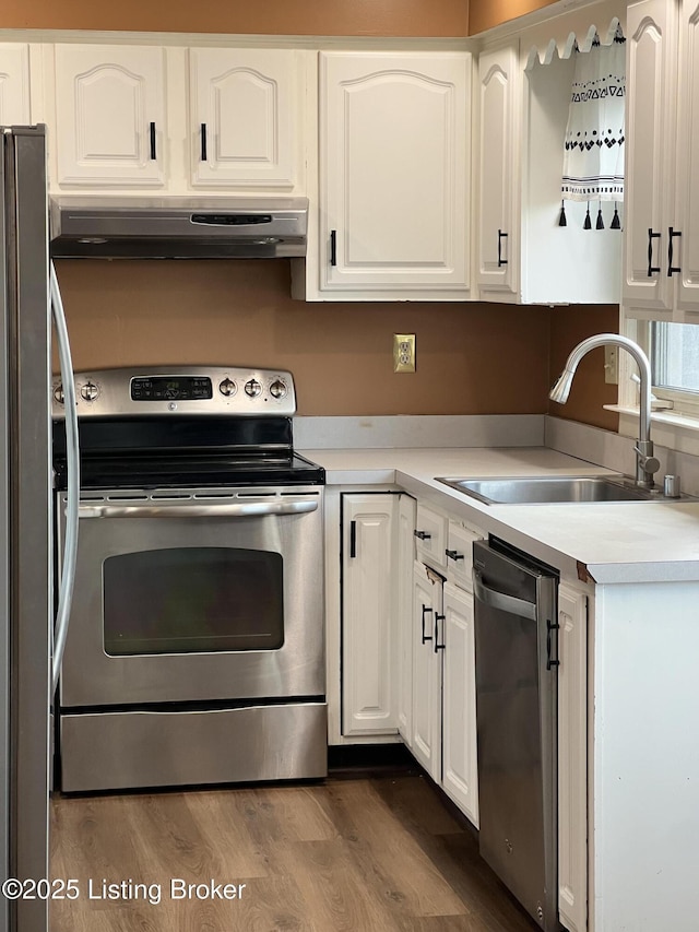 kitchen with dark wood-style flooring, a sink, appliances with stainless steel finishes, white cabinetry, and exhaust hood