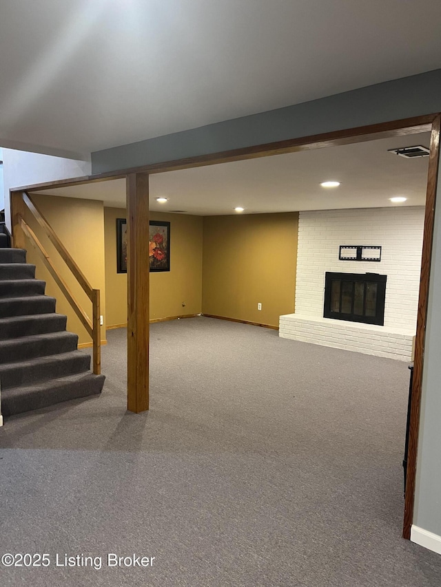 finished below grade area with a brick fireplace, baseboards, stairs, carpet floors, and recessed lighting