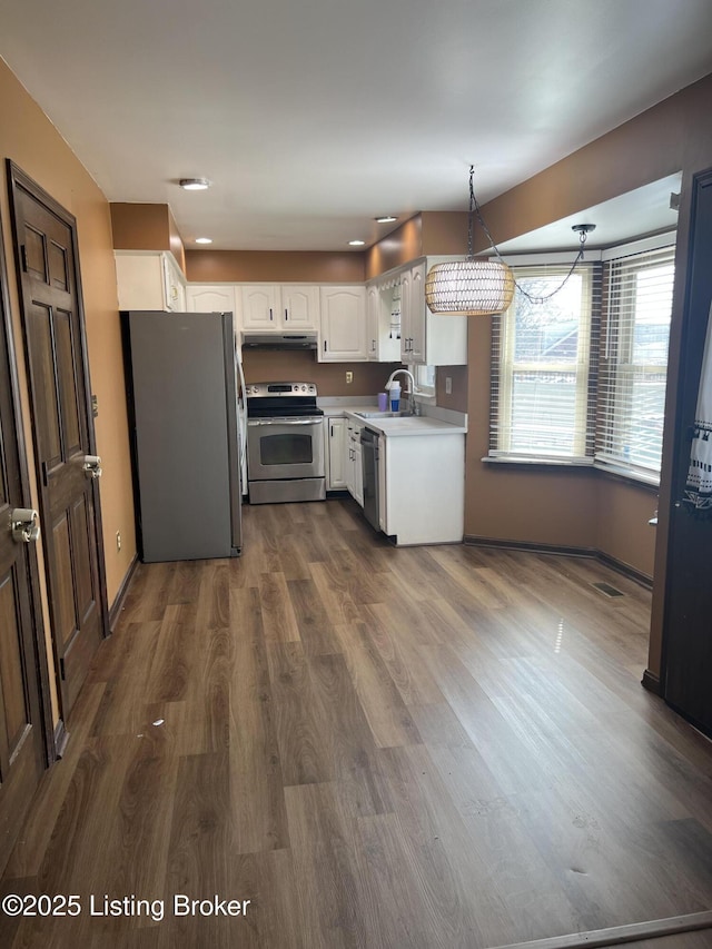 kitchen featuring a sink, dark wood finished floors, appliances with stainless steel finishes, white cabinets, and light countertops