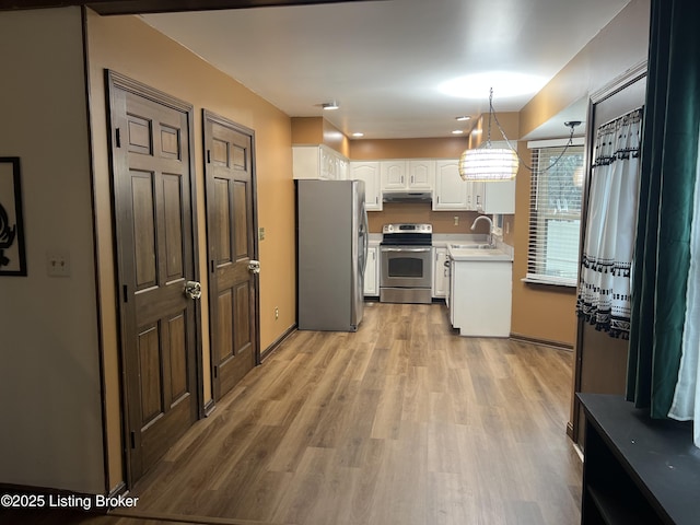 kitchen with under cabinet range hood, stainless steel appliances, light wood-style floors, white cabinets, and light countertops