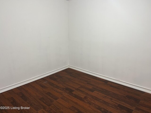 spare room with dark wood finished floors and baseboards