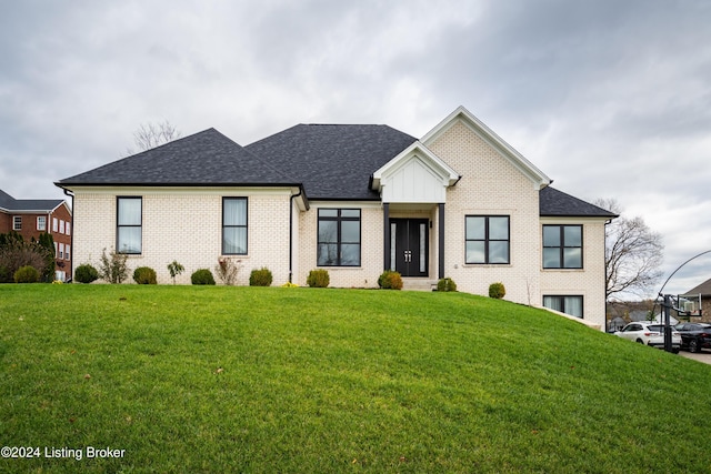 modern inspired farmhouse featuring brick siding, a shingled roof, and a front lawn