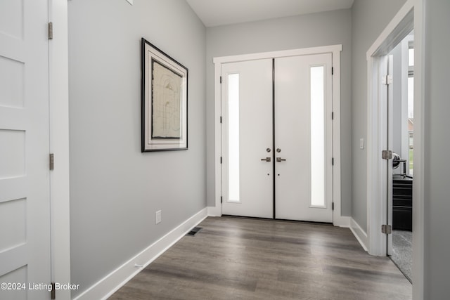 foyer entrance with visible vents, baseboards, and dark wood-style flooring