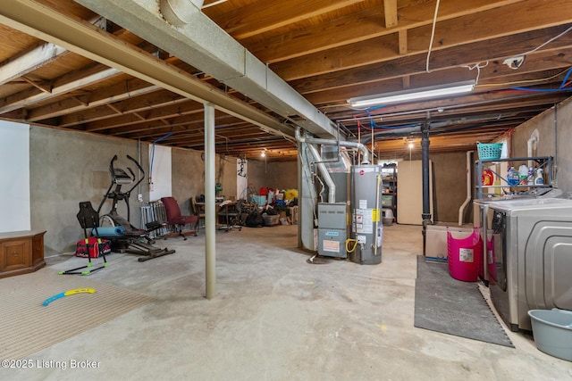 unfinished below grade area featuring heating unit, water heater, and washer and clothes dryer