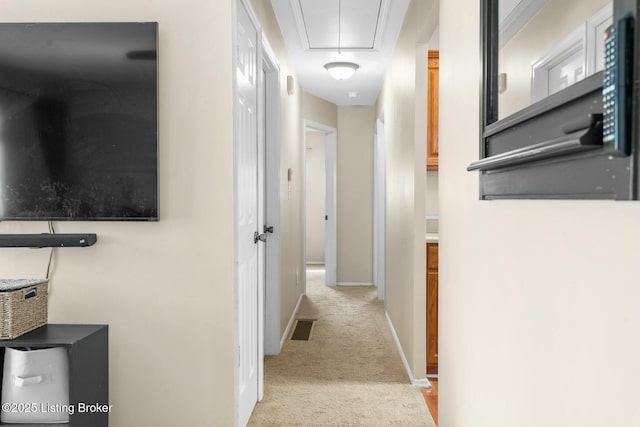 hall with visible vents, attic access, baseboards, and carpet floors