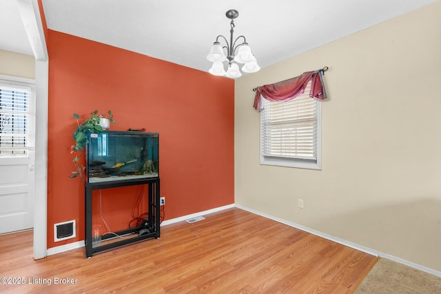 dining space with baseboards, wood finished floors, visible vents, and a chandelier